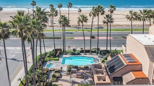 Un hôtel situé en bord de mer, doté d’une piscine, de palmiers et offrant une vue sur l’océan.