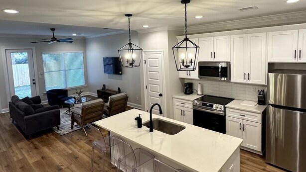 Una cocina moderna con armarios blancos, electrodomésticos de acero inoxidable y una isla central con pileta.
