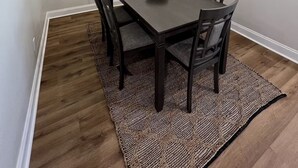 Comedor con una mesa de madera oscura, seis sillas, un tapiz tejido y una lámpara moderna.
