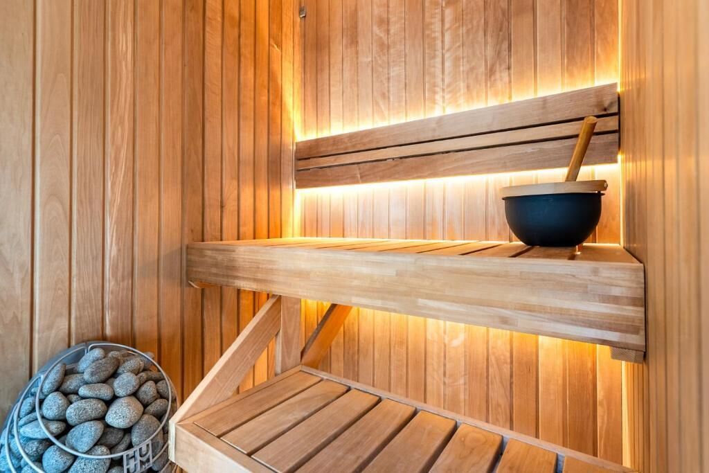 En træsauna med træbænk, en skål og en spand med sten.