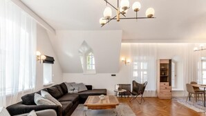 A modern living room with a sectional sofa, a coffee table, and a dining area with chairs and a table. - Luxury 2BD apartment in City Center (Tallinn)