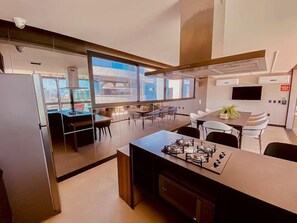 Una cocina moderna con estufa a gas, comedor con sillas y un amplio ventanal con vista a la ciudad.