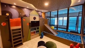 Un cuarto de juegos infantil con literas, un tobogán y una piscina de pelotas.