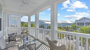 A covered porch with wicker furniture, a ceiling fan, and a view of neighboring houses. - Resorting To Happiness by Avantstay Close to the Beach, w/ Pool Access (Panama City Beach)