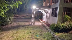 Vista nocturna de un edificio con una entrada bien iluminada y un arco decorativo.