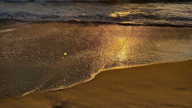 Une plage avec des vagues et un coucher de soleil.