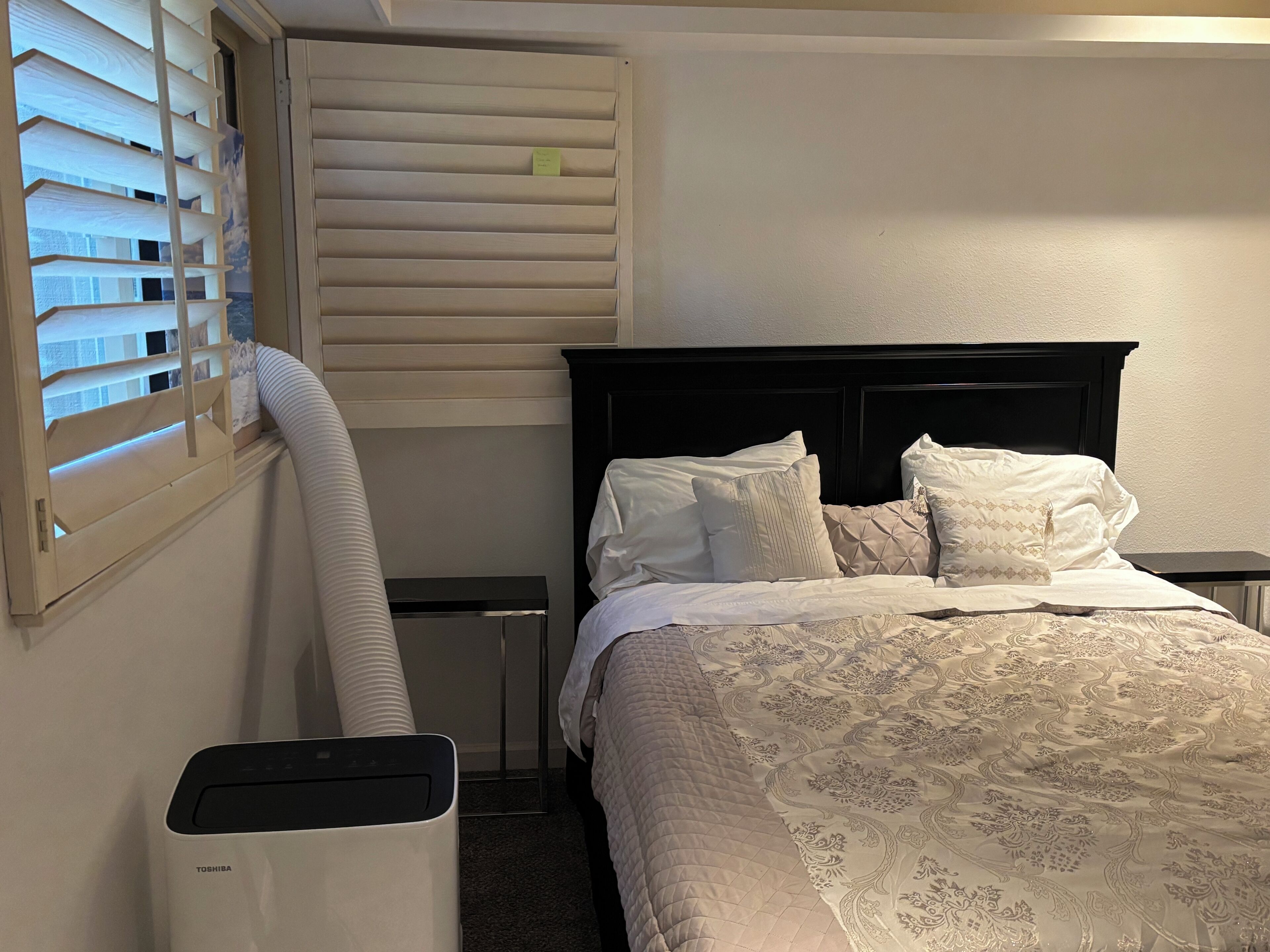 Une chambre d’hôtel avec un lit, une table de chevet, un radiateur et une fenêtre avec des stores.
