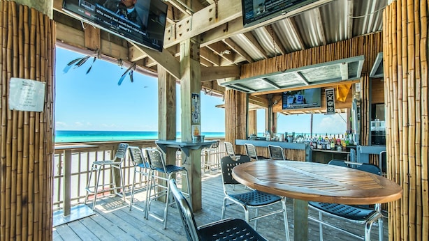 A wooden deck with a round table and chairs, overlooking a beach. - Surfside Resort #404 (Miramar Beach)