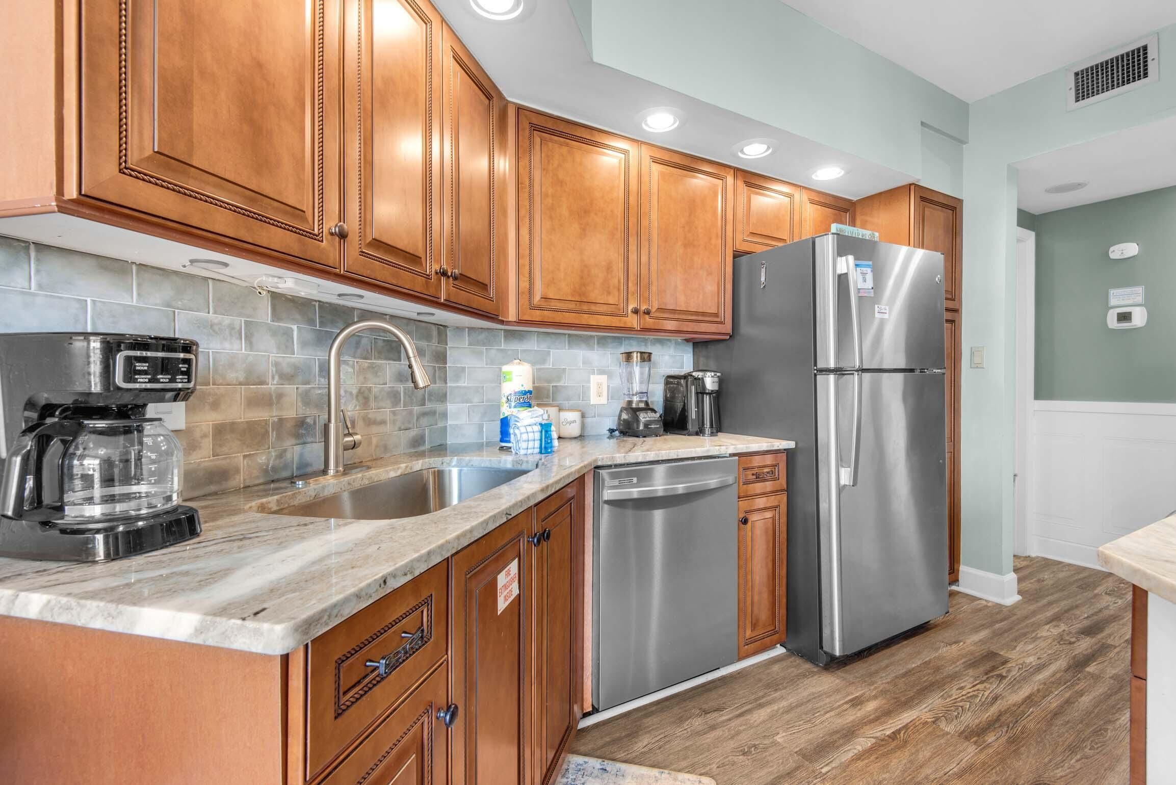 A modern kitchen with wooden cabinets, stainless steel appliances, and a tiled backsplash.
