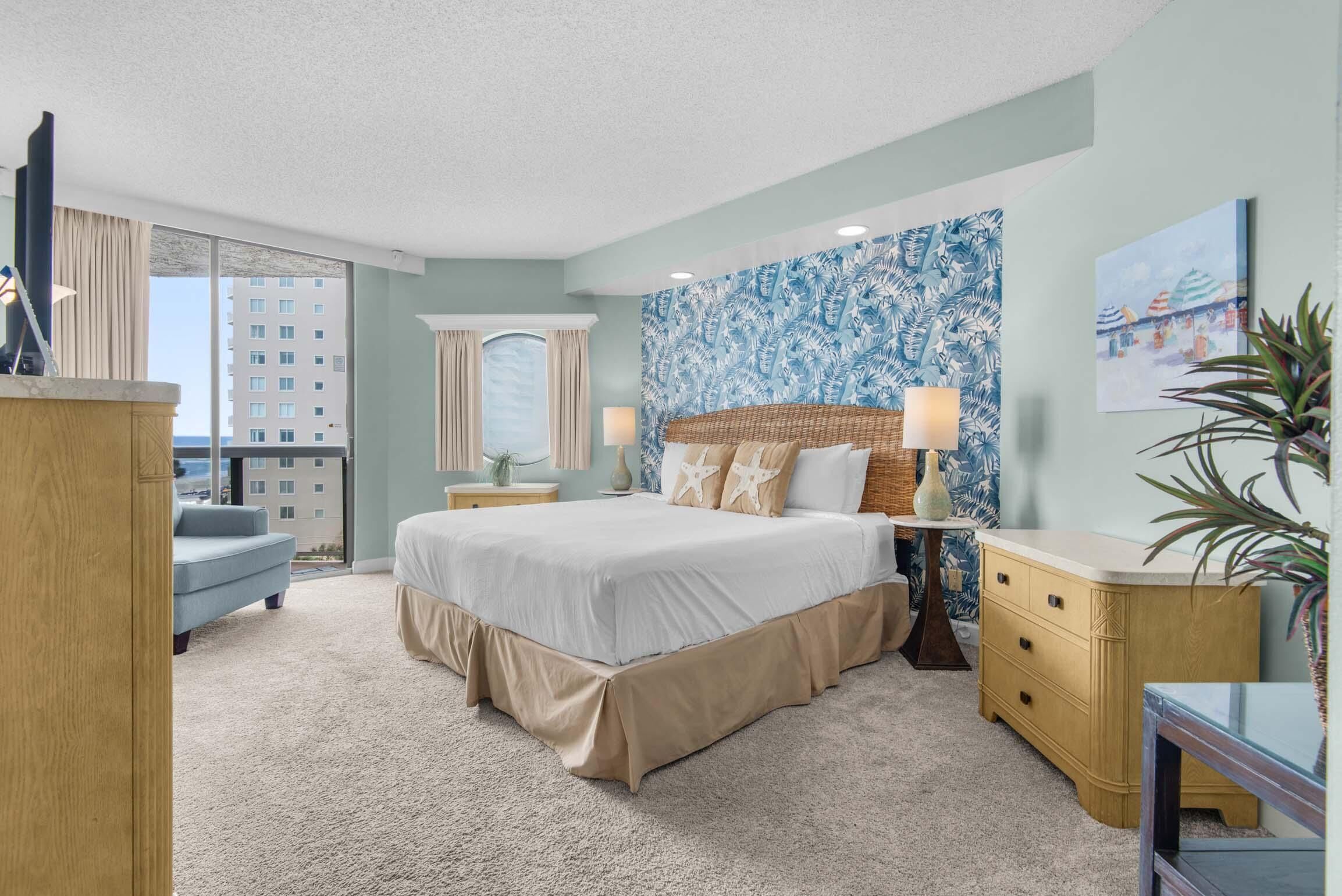 A bedroom with a large bed, a nightstand, a dresser, and a window with curtains.