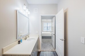 A modern bathroom with a double sink, a large mirror, and a walk-in shower. - Landing | Chic 2BD, Pool, Gym (Park Hills)