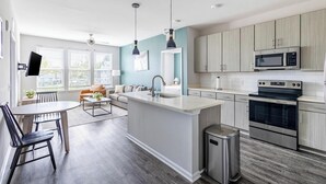 A modern kitchen with a central island, stainless steel appliances, and light wood cabinets. - Landing | Amazing 2BD, Pool, Clubhouse (Park Hills)