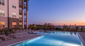 A rooftop pool with lounge chairs and a city view at sunset. - Landing | Chic 2BD, Pool, Gym (Park Hills)
