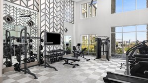 A modern gym with various exercise equipment, large windows, and a city view. - Landing | Amazing 2BD, Pool, Clubhouse (Park Hills)