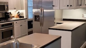 Una cocina moderna con armarios blancos, electrodomésticos de acero inoxidable y una isla central.