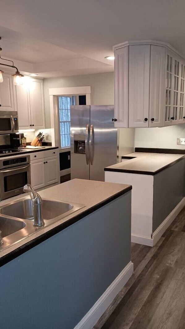 A modern kitchen with white cabinetry, stainless steel appliances, and a central island.