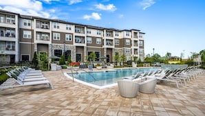 A modern apartment building with a swimming pool, lounge chairs, and outdoor seating. - Landing | Incredible 2BD, Pool, Yoga Studio (Florence)