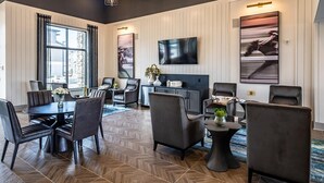 A modern hotel room with a dining area, a flat-screen TV mounted on the wall, and a large window with curtains. - Landing | Incredible 2BD, Pool, Yoga Studio (Florence)