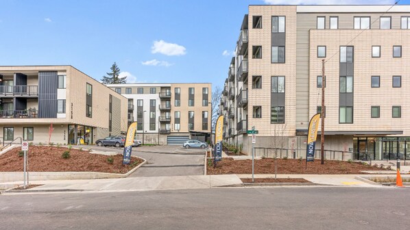 A modern apartment complex with multiple buildings, a gated entrance, and a landscaped area with trees. - Landing | Amazing 2BD, Gym (Portland)