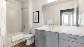 A modern bathroom with a shower, toilet, and vanity. - Landing | Amazing 2BD, Gym (Portland)