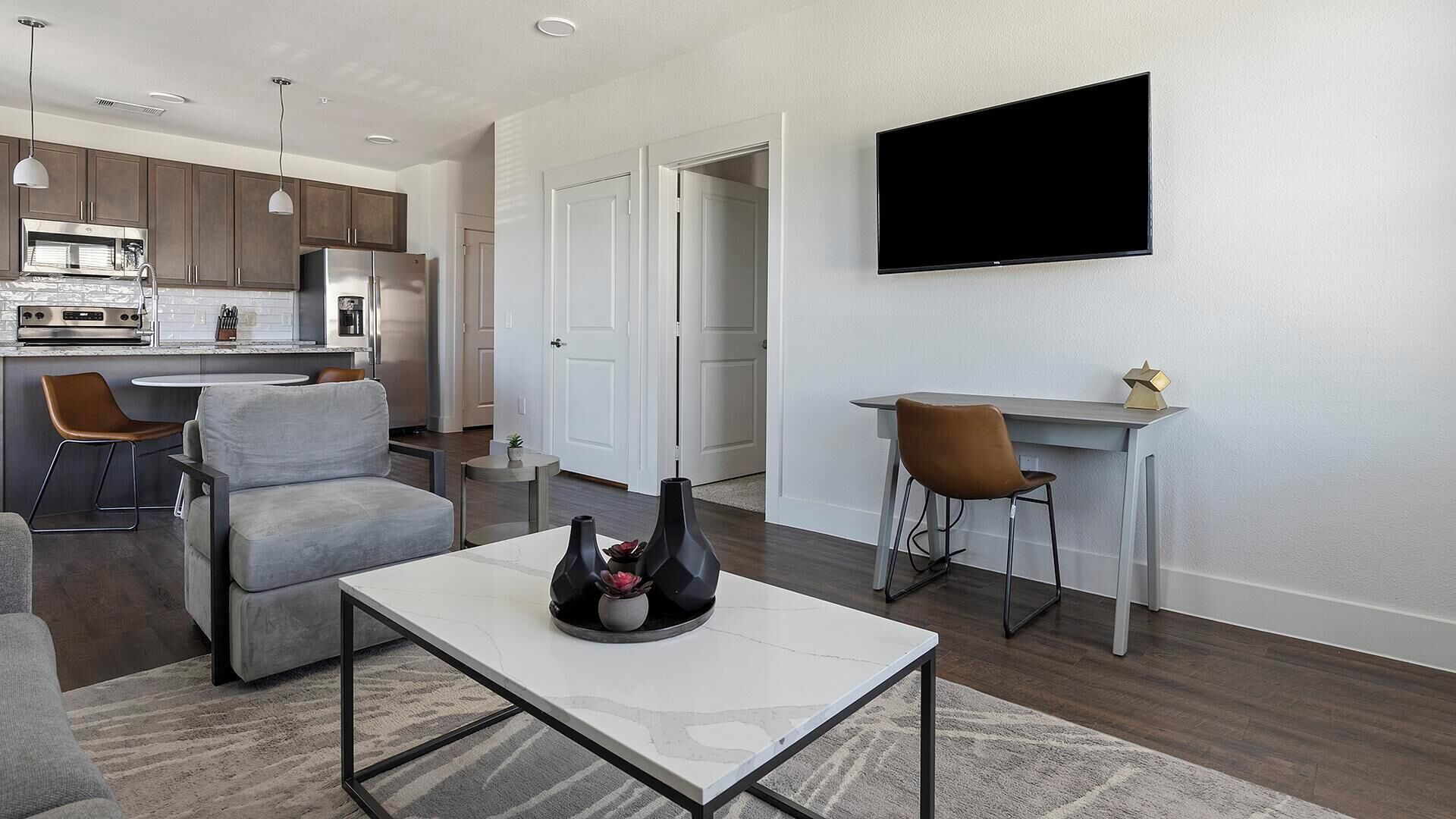 Un salon moderne avec un canapé, une table basse et un téléviseur fixé au mur.
