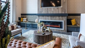 Ein modernes Wohnzimmer mit Kamin, gemütlicher Sitzgelegenheit und großem Fernseher.