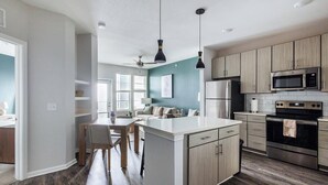 Una cocina moderna con una isla central, electrodomésticos de acero inoxidable e iluminación colgante.