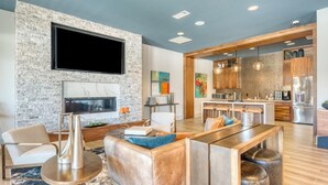 Una sala moderna con pared de piedra, un televisor de pantalla plana y un comedor con taburetes.