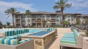 Zona de piscina de hotel con sillones de descanso y una piscina con borde de piedra.