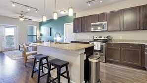 Una cocina moderna con armarios de madera oscura, electrodomésticos de acero inoxidable y una isla central con taburetes de bar.