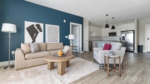 Uma sala de estar moderna com sofá, mesa de centro e área de jantar com uma cadeira e mesa lateral.