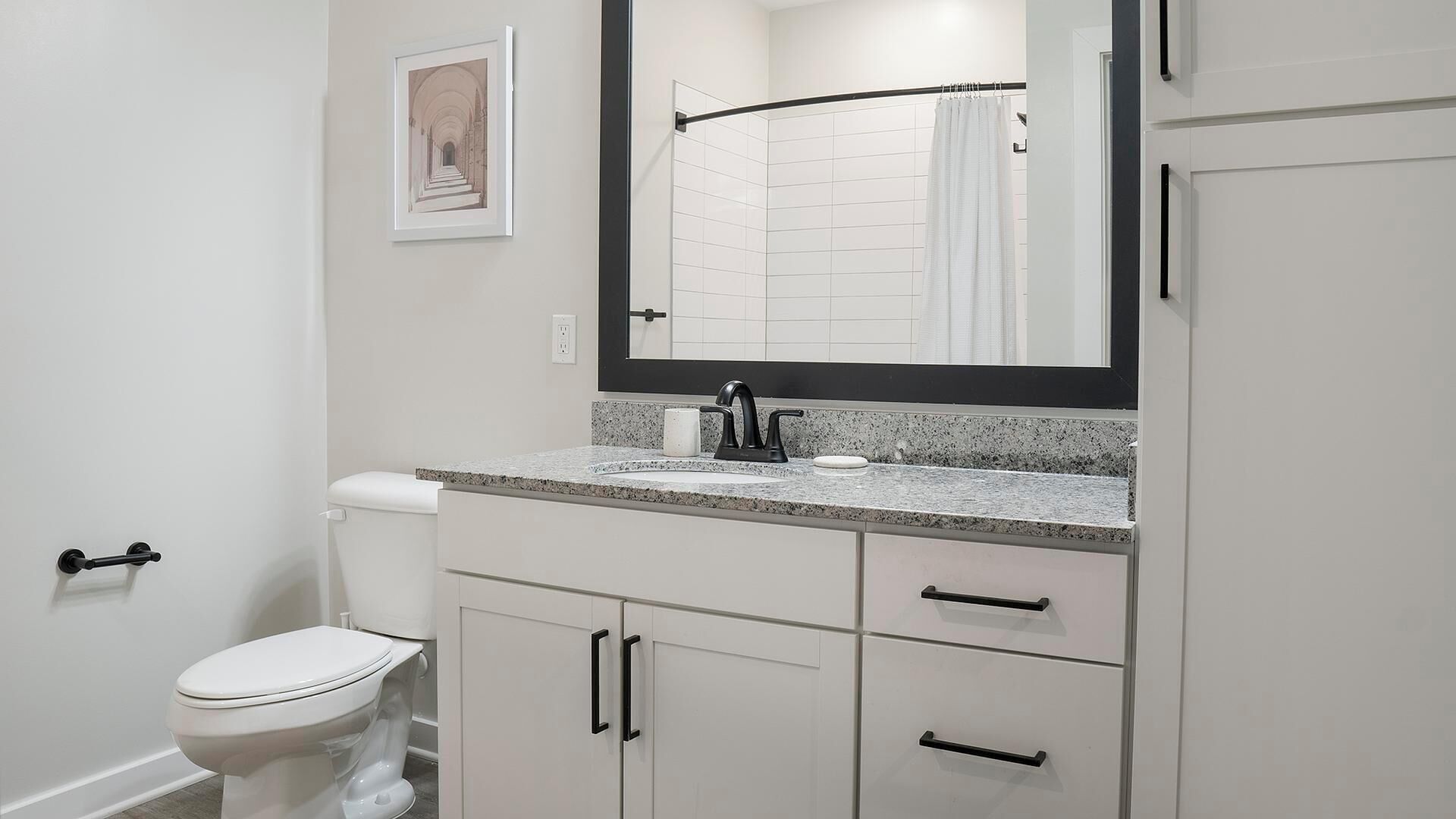 A modern bathroom with a toilet, sink, and mirror.