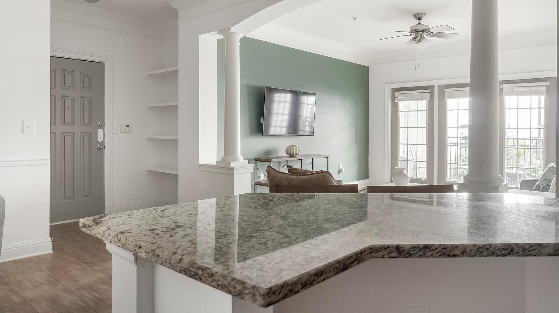 A spacious kitchen with a granite countertop, a dining area with a table and chairs, and a large window providing natural light.