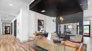 Un hall d’hôtel moderne avec un comptoir d’accueil en bois, un espace salon et une grande fenêtre donnant sur la rue.