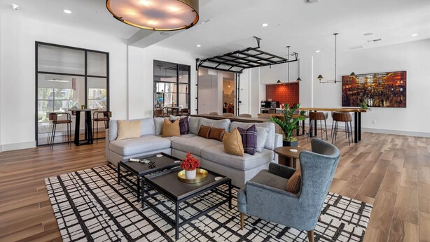 Un salon moderne avec un canapé d’angle, une table basse et un coin repas doté d’un bar.