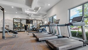 Une salle de sport équipée de tapis de course, d’appareils de musculation et d’un banc.