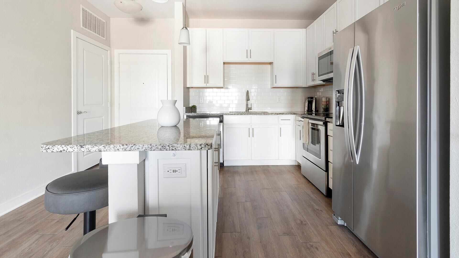 A modern kitchen with white cabinets, stainless steel appliances, and a granite countertop.