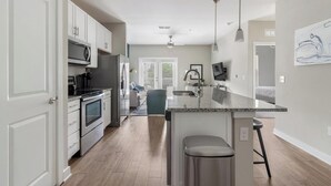 Une cuisine moderne avec des armoires blanches, des appareils en acier inoxydable et un comptoir en granit.
