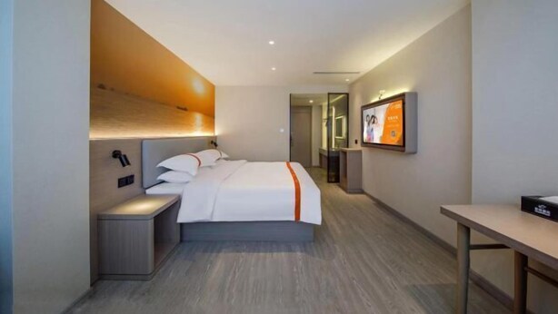 Une chambre d’hôtel moderne équipée d’un lit, de tables de chevet, d’un bureau et d’une télévision.