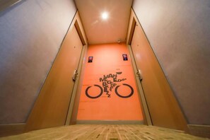 A narrow, brightly lit stairway leading to a door with a bicycle graphic. - Shell Hotel (Jingjiang Taihe Wuyue Plaza Bus Station) (Jingjiang)