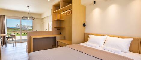 A modern hotel room with a large bed, built-in closet, desk, and a balcony with a view.