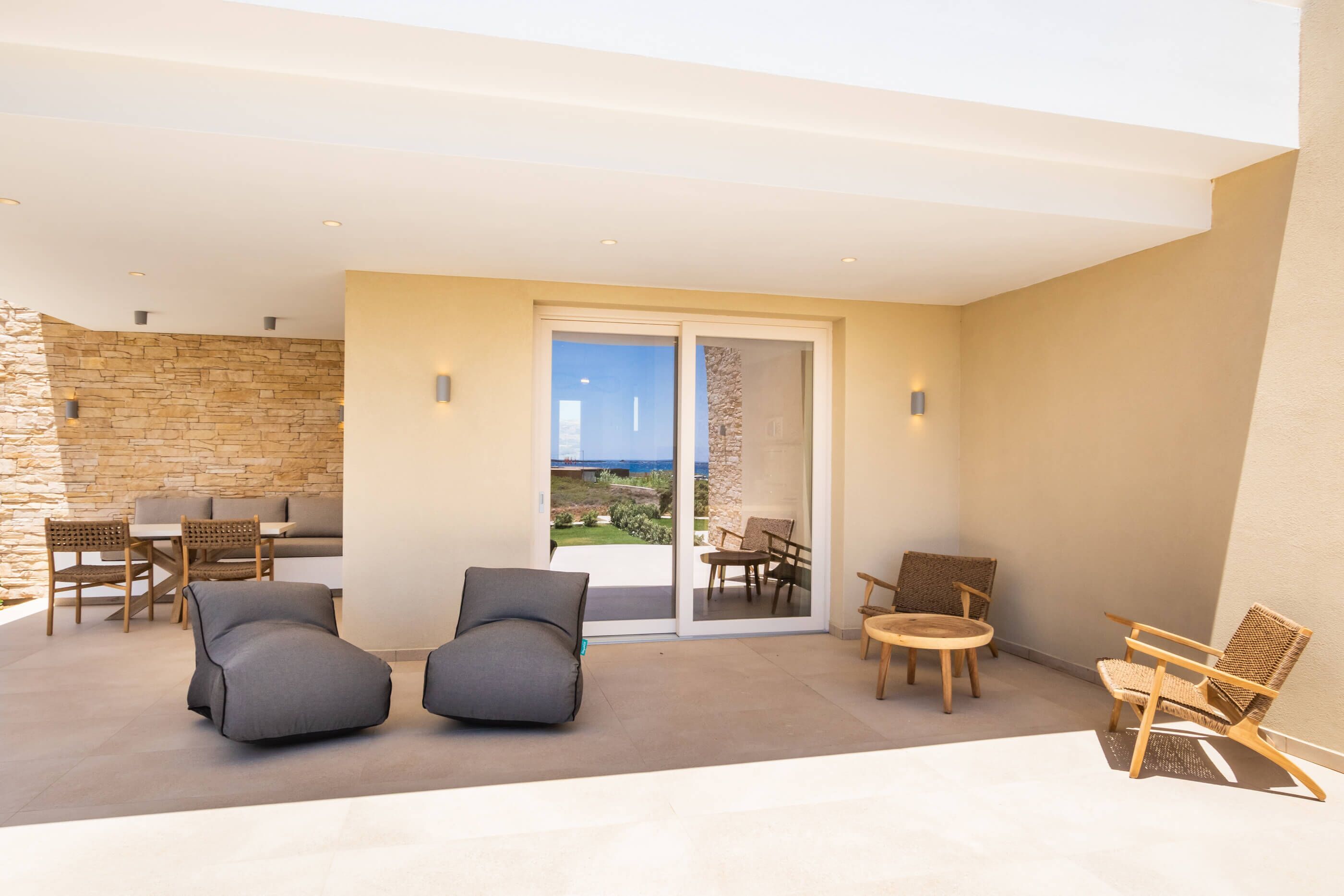 A modern outdoor patio with a stone wall, a dining set, and two lounge chairs.