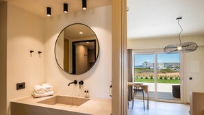 A modern bathroom with a large mirror, a sink, and a view of the outdoor terrace. - Thalassa Suites (Karpathos)