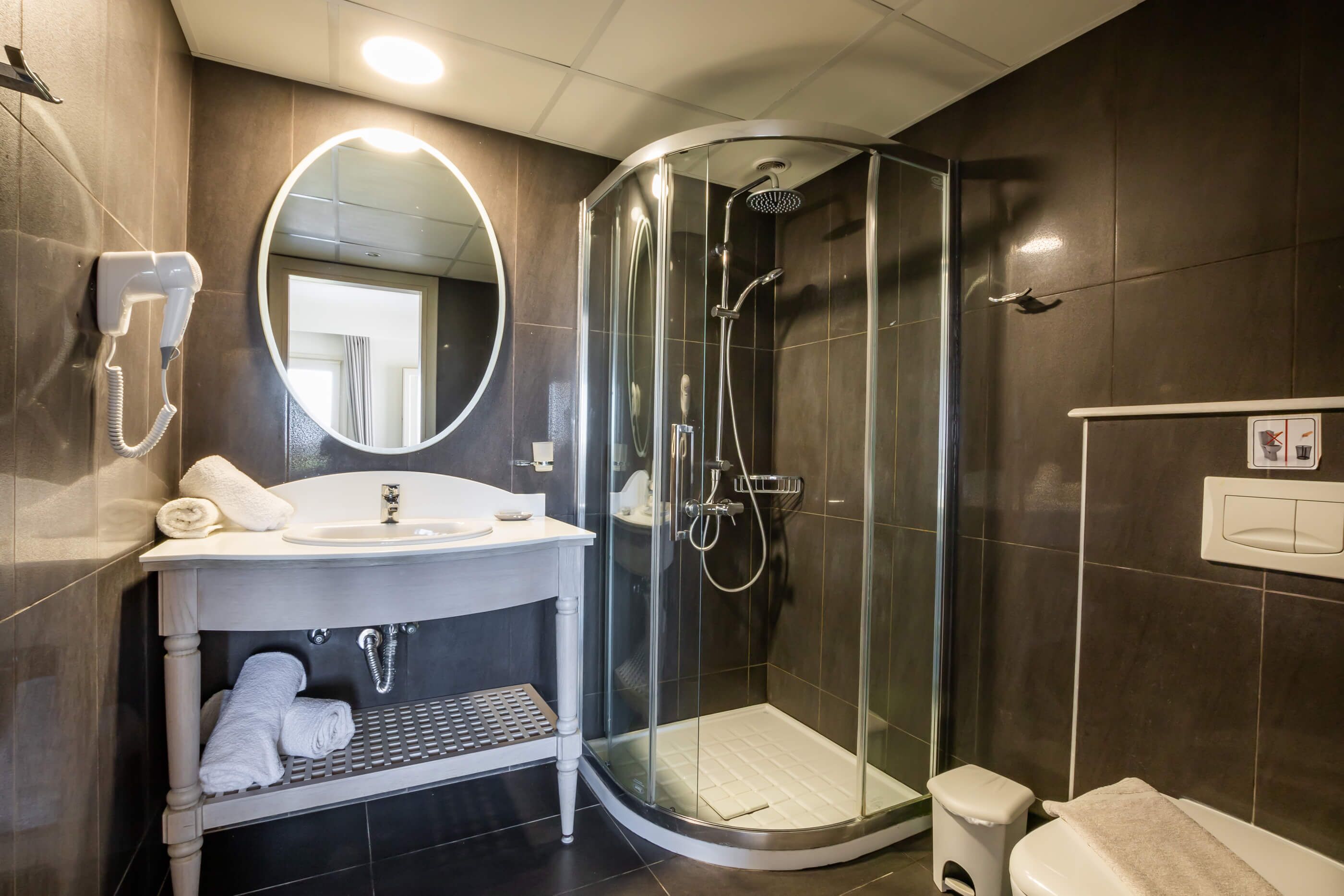 A modern bathroom with a glass-enclosed shower, a vanity with a sink, and a mirror.