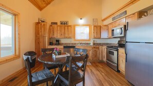 A kitchen with wooden cabinets, a stainless steel refrigerator, and a dining table with chairs. - Spectacular Mountain Views Near Dollywood (Sevierville)
