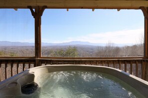 Un bain à remous avec une terrasse en bois et une vue sur les montagnes.