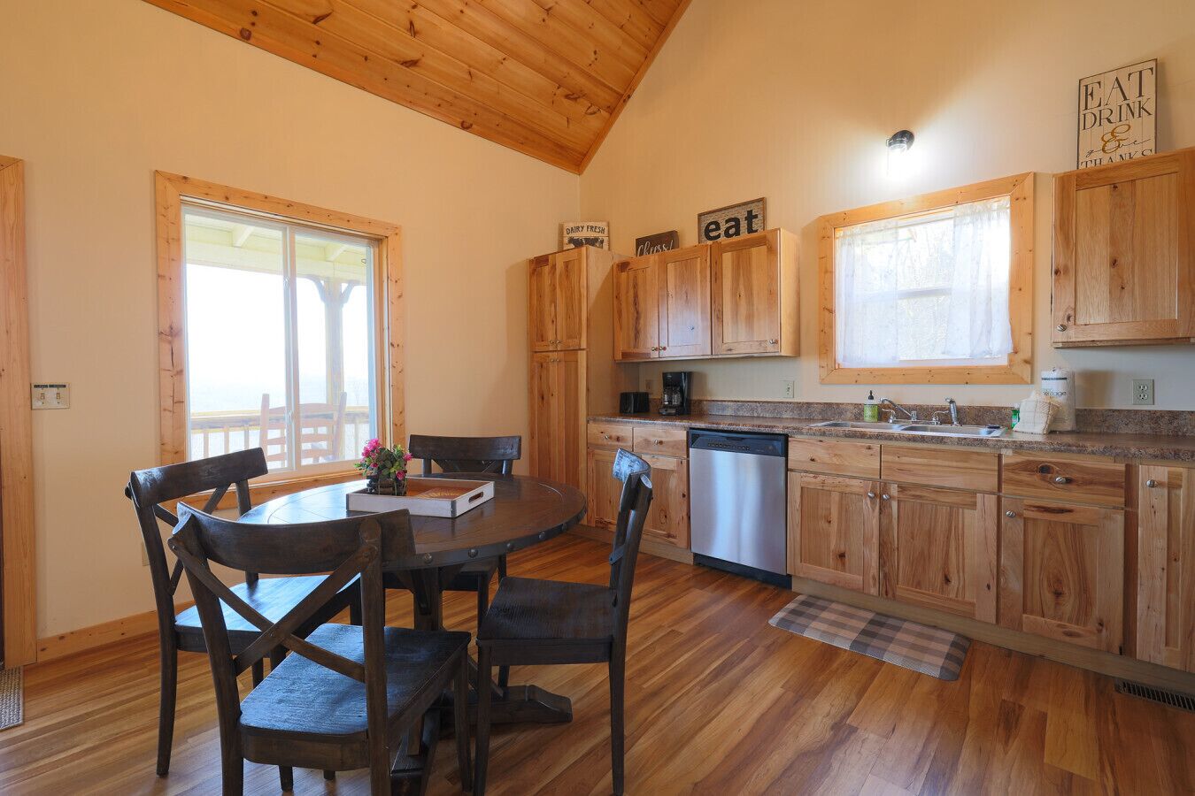 Un intérieur en bois comprenant une table à manger, des chaises, une cuisine avec des meubles en bois et une fenêtre.