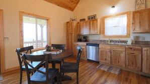 A wooden interior with a dining table, chairs, a kitchen with wooden cabinets, and a window. - Spectacular Mountain Views Near Dollywood (Sevierville)