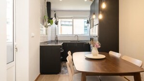 Une cuisine moderne avec des meubles de couleur sombre, un îlot central et des luminaires suspendus.