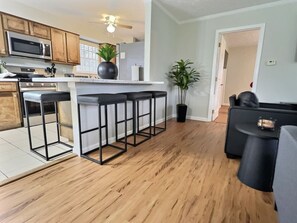 Eine moderne Küche mit Holzausstattung, einer Edelstahl-Mikrowelle und einer Bar mit Hockern.